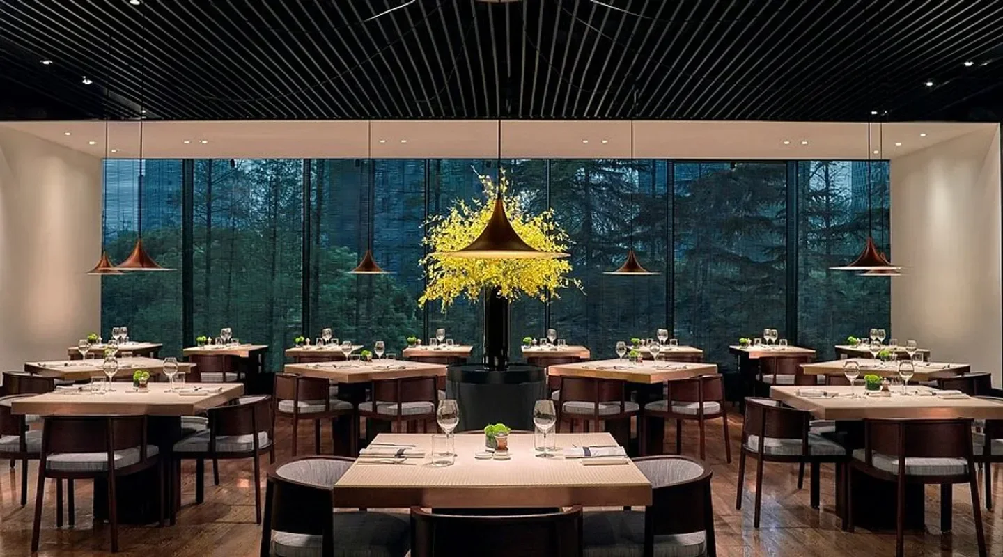 Elegant dining room at Phénix Shanghai restaurant, featuring natural light and forest views.