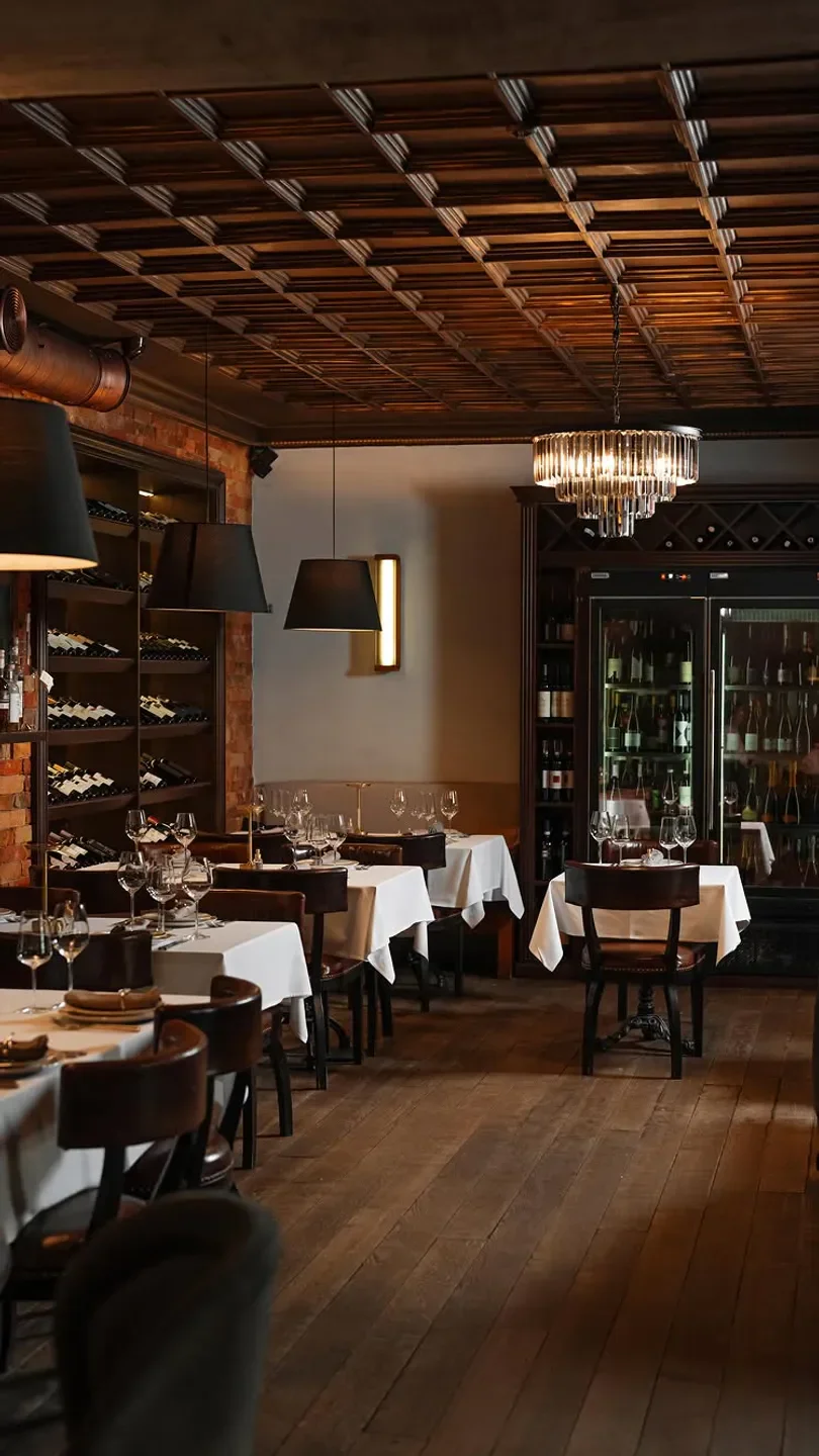 Cozy interior of Piccolino restaurant in Kyiv, featuring tables, wine, and a chandelier.