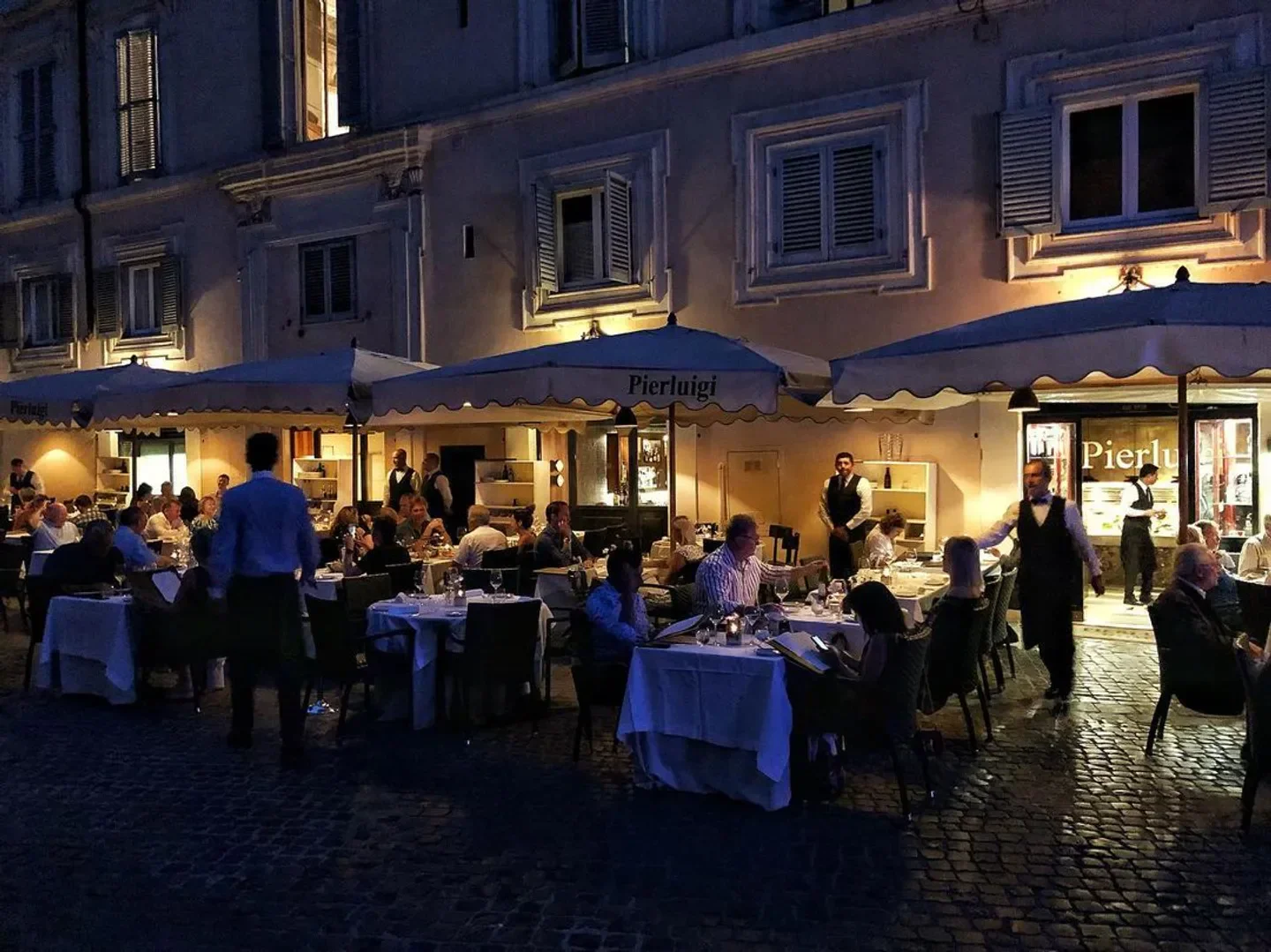 Outdoor dining at Pierluigi restaurant in Rome, featuring elegant tables and ambiance at night.