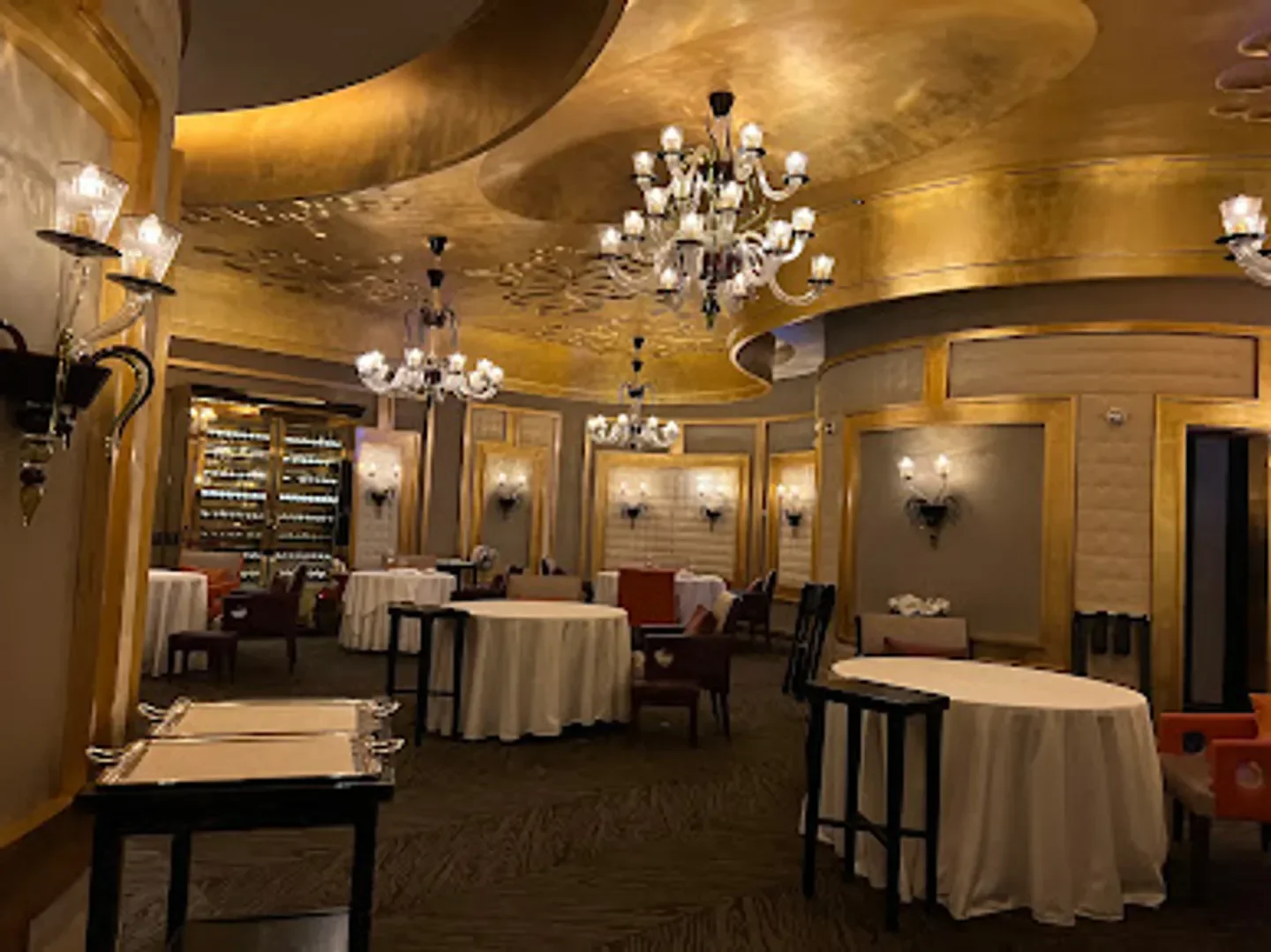 Elegant dining room interior at Pierre Gagnaire in Seoul, with chandeliers and round tables.