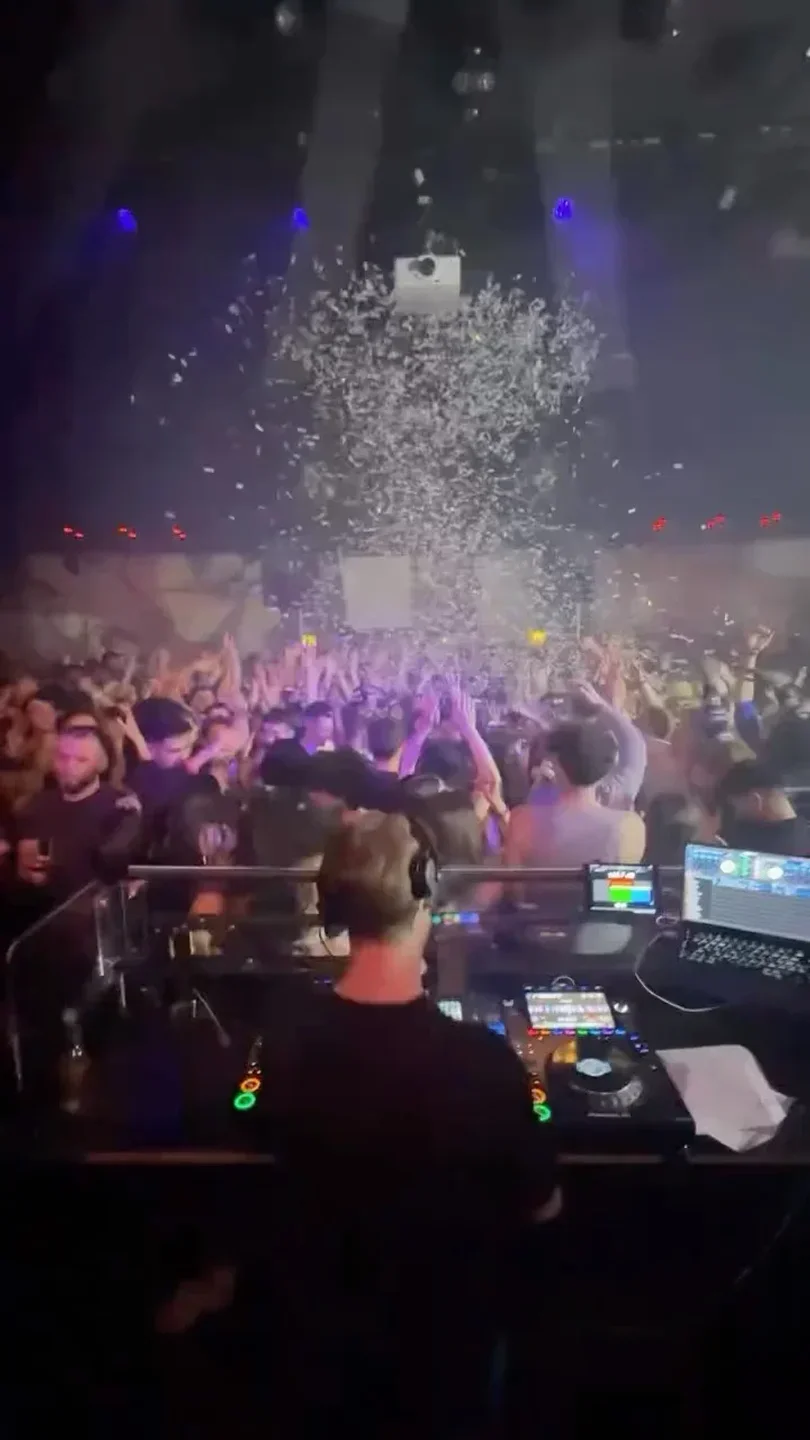 DJ at Plaza Zurich nightclub with crowd, confetti and vibrant lights.