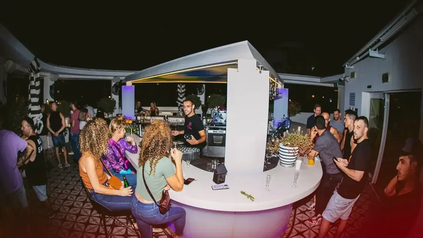 Nightlife at Poli House Rooftop beach club in Tel Aviv, with bar and lively crowd