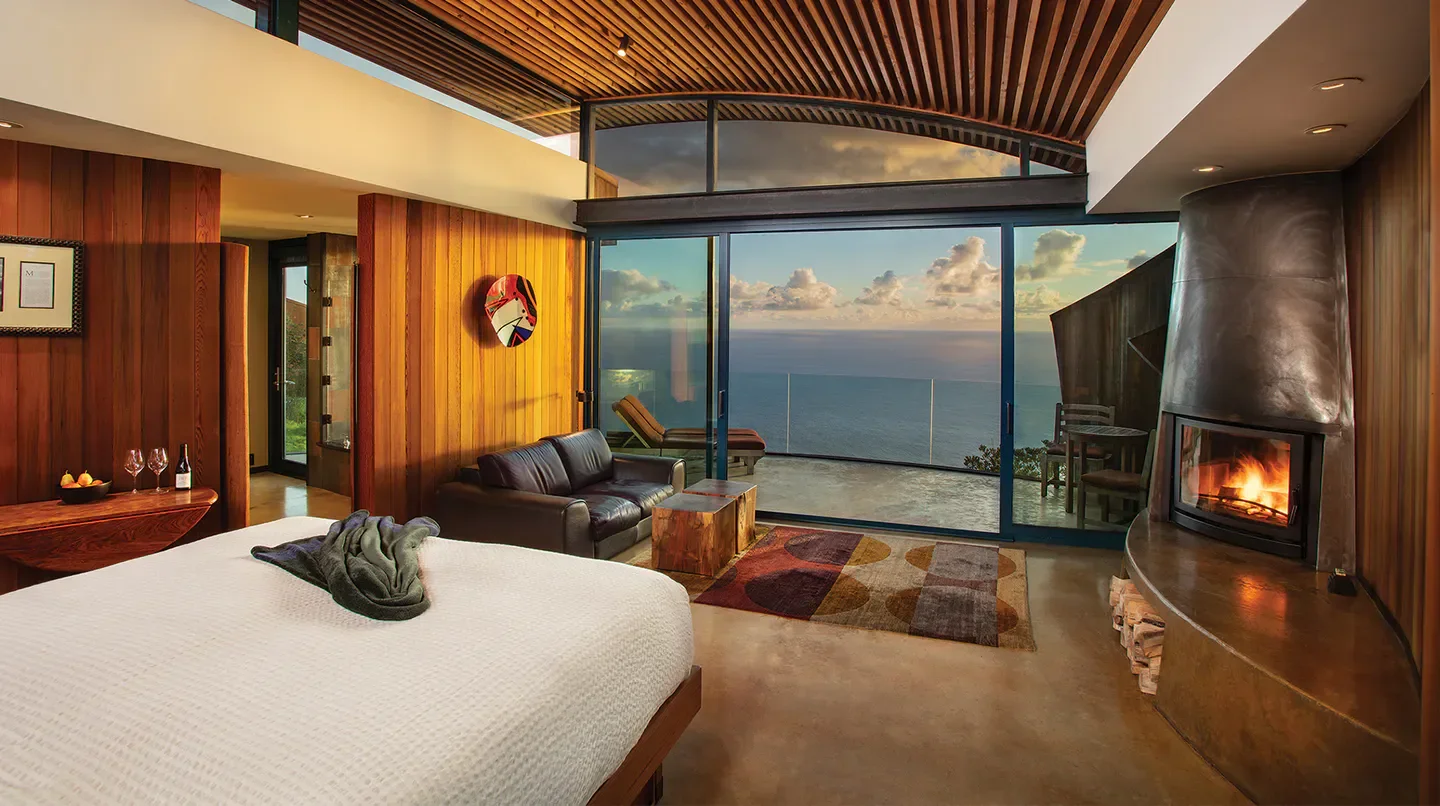 Cozy room with ocean view at Post Ranch Inn in Monterey, California, with a fireplace.