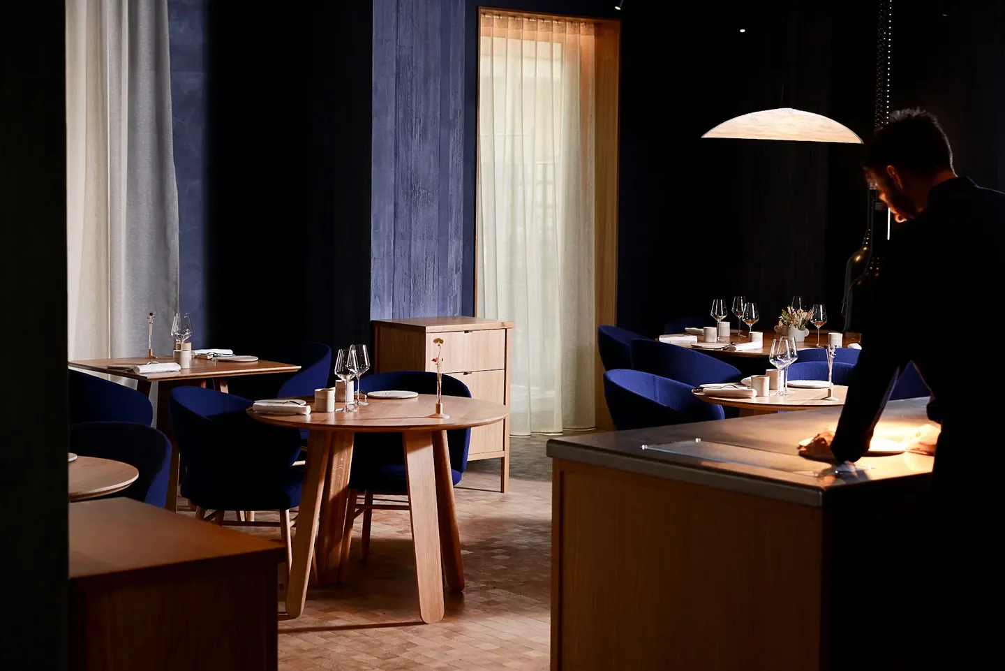 Interior of Prairial restaurant in Lyon, featuring elegant table settings and dark blue chairs.