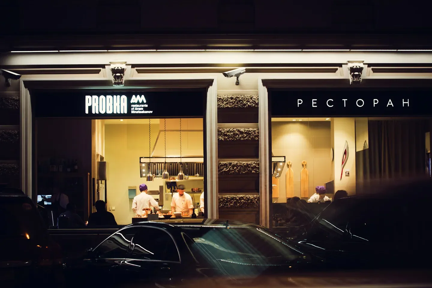 Exterior view of Probka restaurant in St Petersburg at night, chefs working inside.