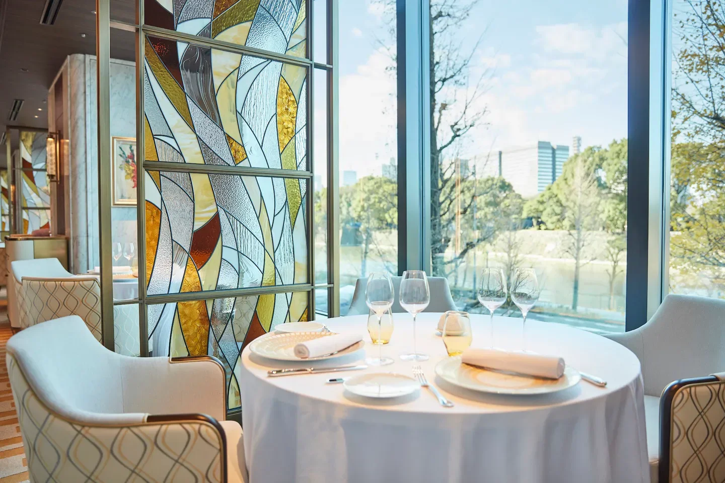 Elegant dining at PRUNIER Tokyo restaurant, featuring a stained glass window with a view