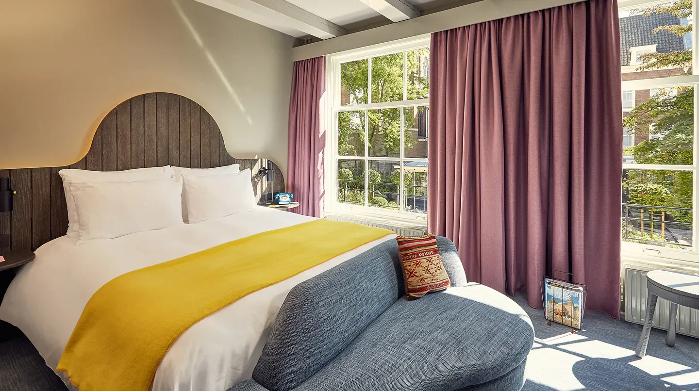Cozy bedroom at Pulitzer Amsterdam in Amsterdam, featuring a large bed and window.