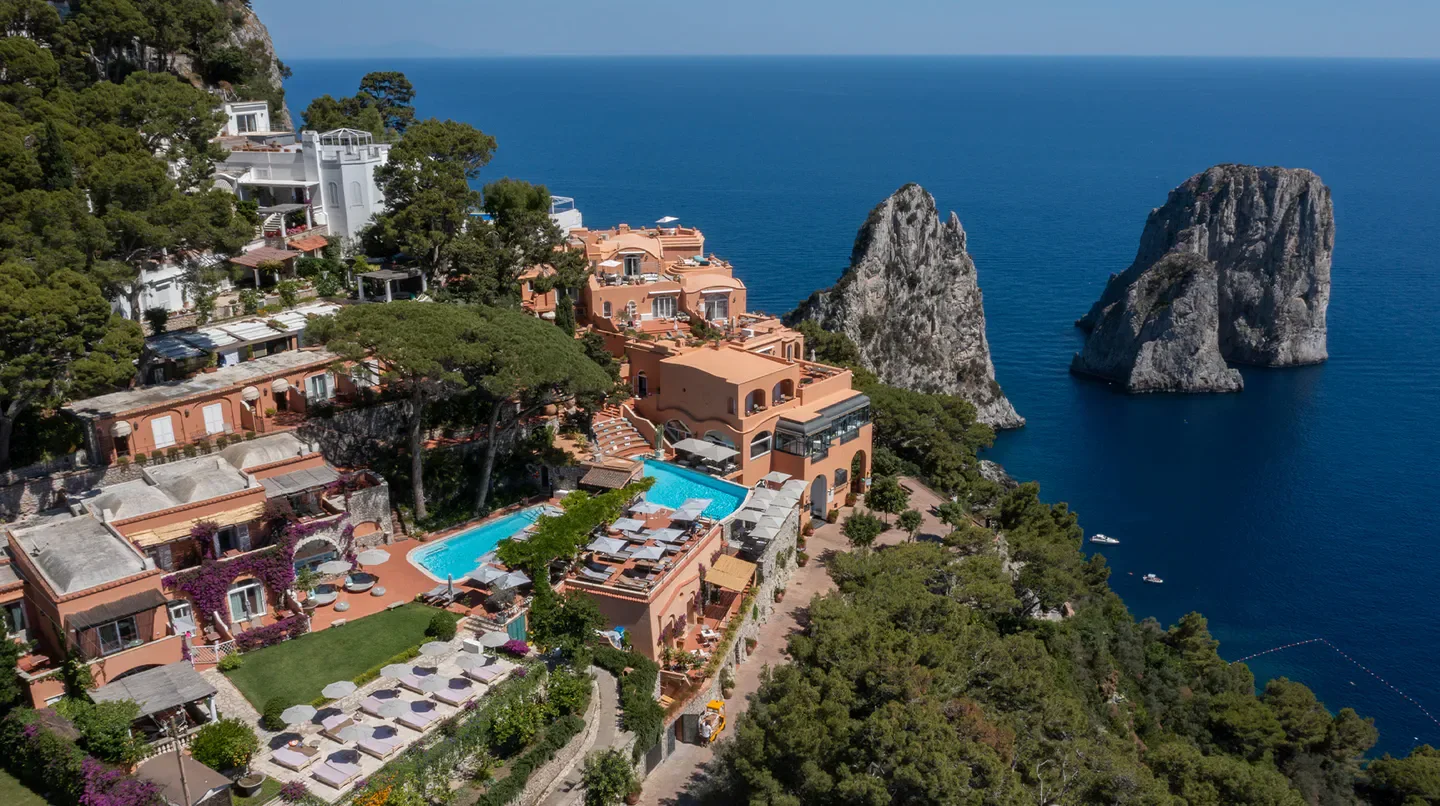 Aerial view of the Punta Tragara Hotel in Capri, featuring pool and scenic coastal views.