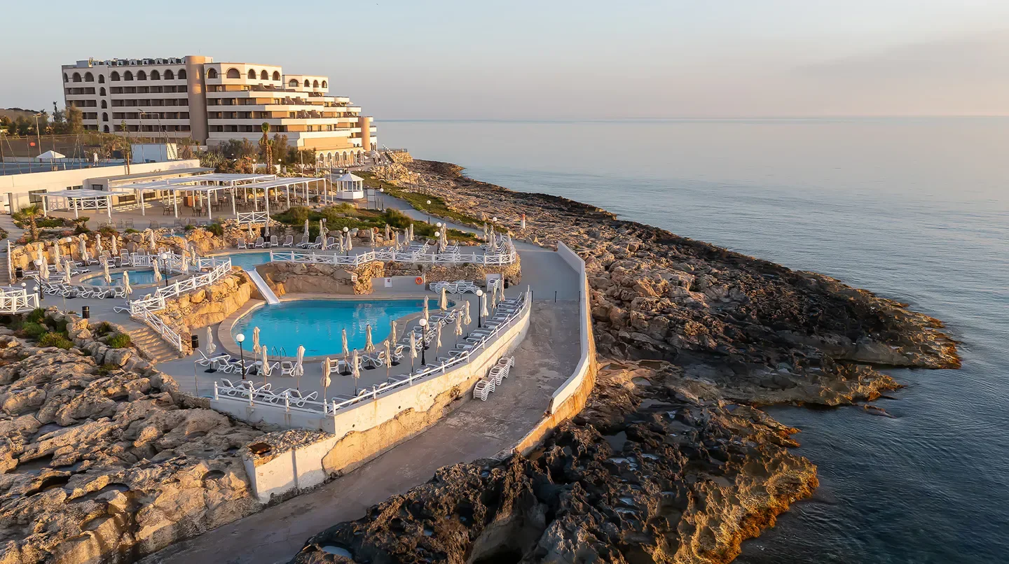 Pools and shoreline at Radisson Blu Resort, St Julian's, Malta, during sunset.