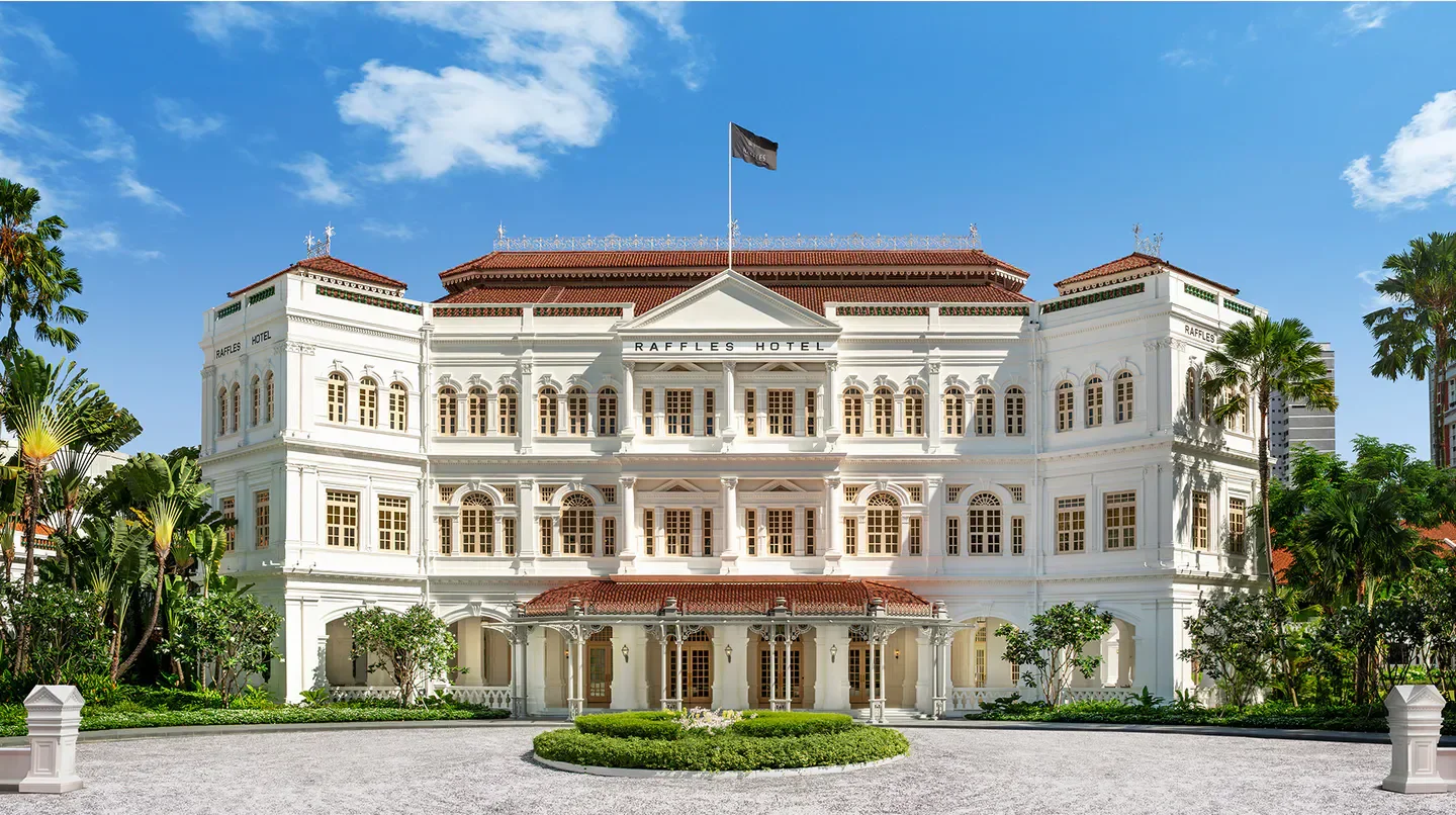 Iconic exterior of Raffles Hotel Singapore, a luxury hotel in Singapore, under a blue sky.