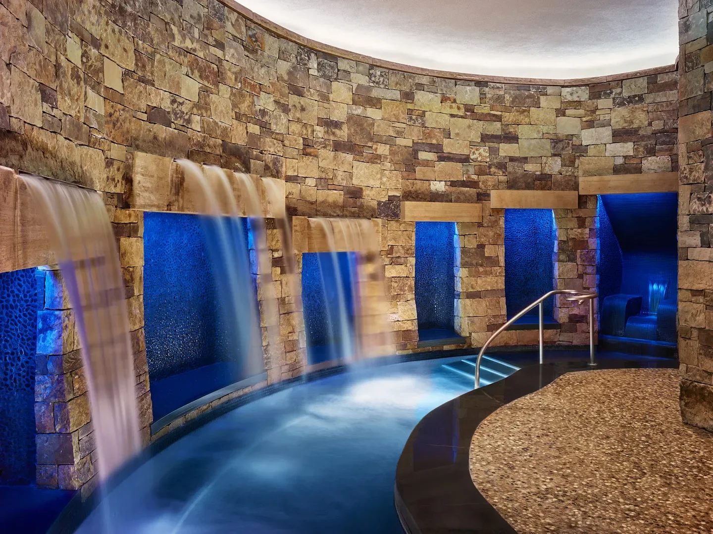 Interior of RAKxa Wellness Spa at The St. Regis Aspen Resort with waterfalls and stone walls.