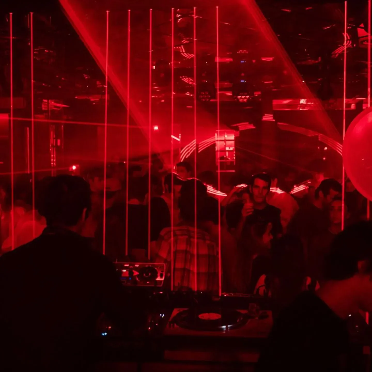 Red Room nightclub in Milan, with a DJ and red laser lights over a crowd.