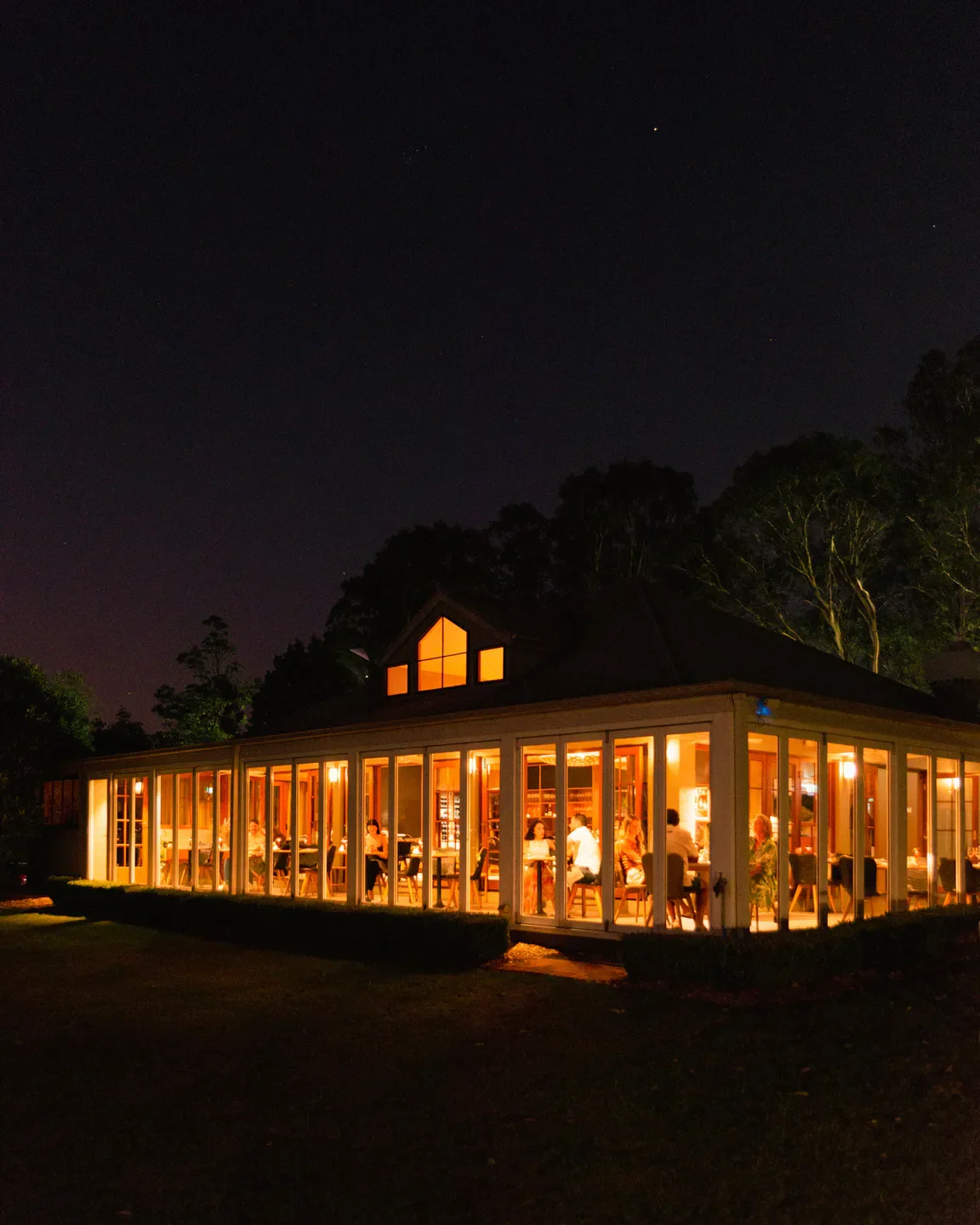 Restaurant Botanica in Hunter Valley at night, with diners visible inside.