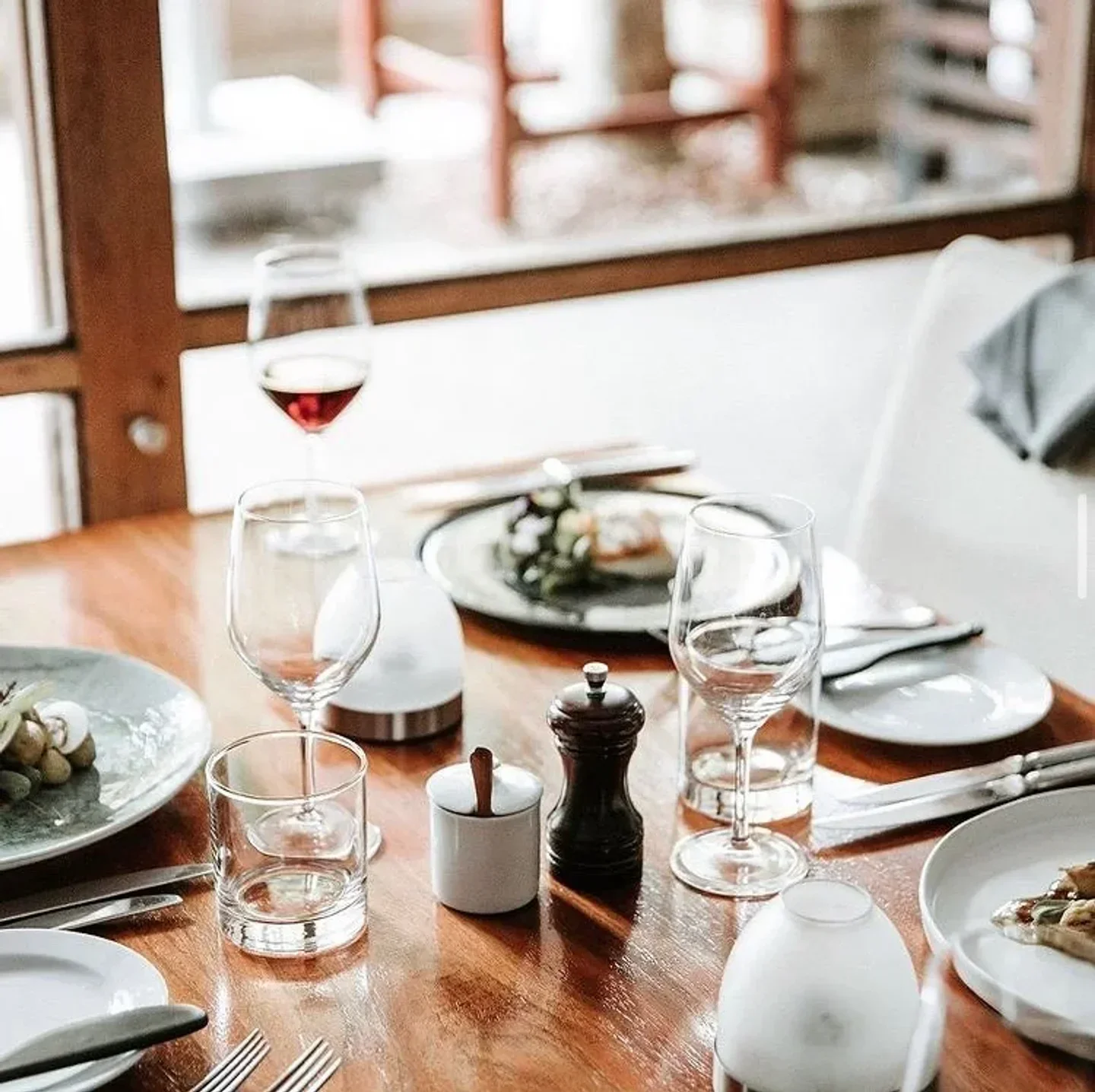 Table setting at Restaurant Mason in Newcastle, with wine glasses and plates of food.