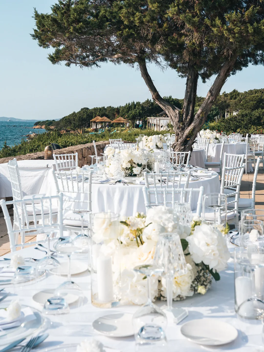 Elegant outdoor wedding reception setup at Rocca Beach Club, Porto Cervo, with white floral arrangements and sea views.