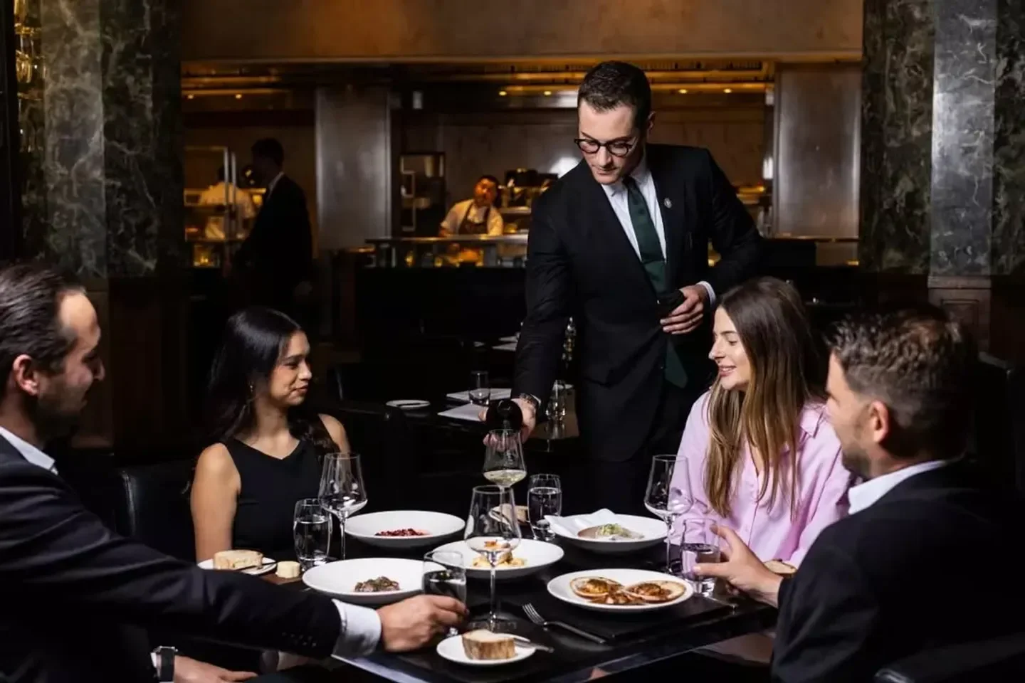 Rockpool Bar and Grill Melbourne: Waiter pours wine for diners at an elegant table.