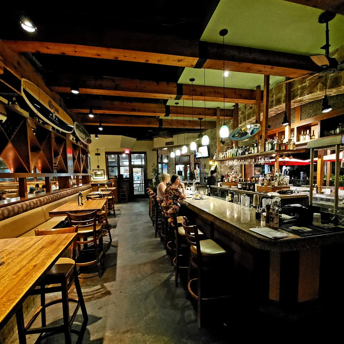 Cozy bar interior at Romano restaurant in Tuscany, featuring wooden beams and surfboards.
