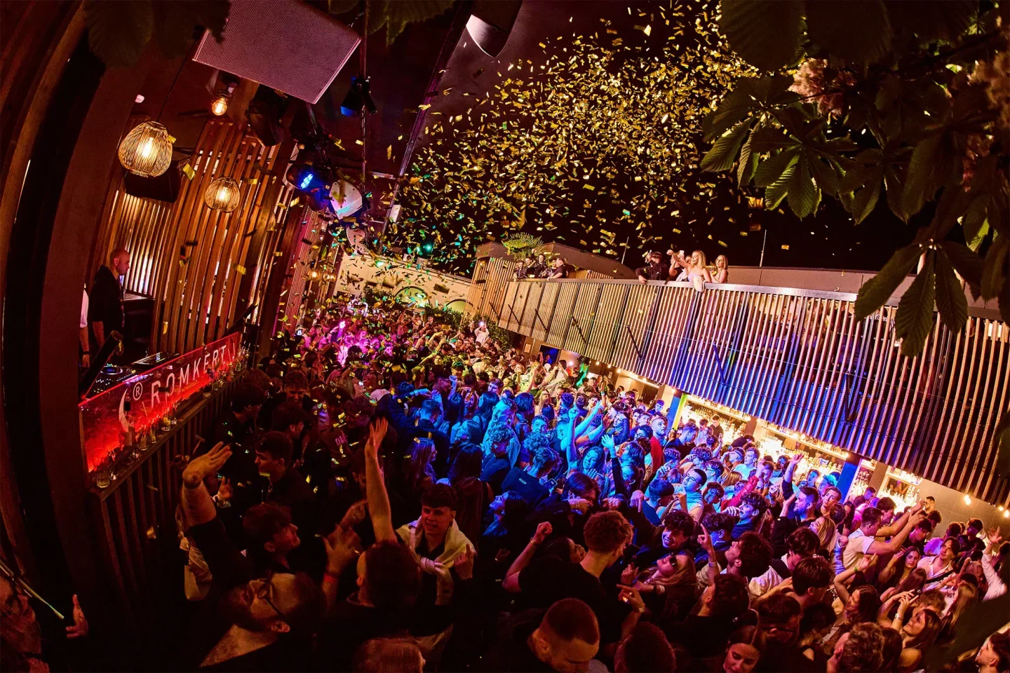 Energetic party at Romkert nightclub in Budapest, confetti falling on the crowd.