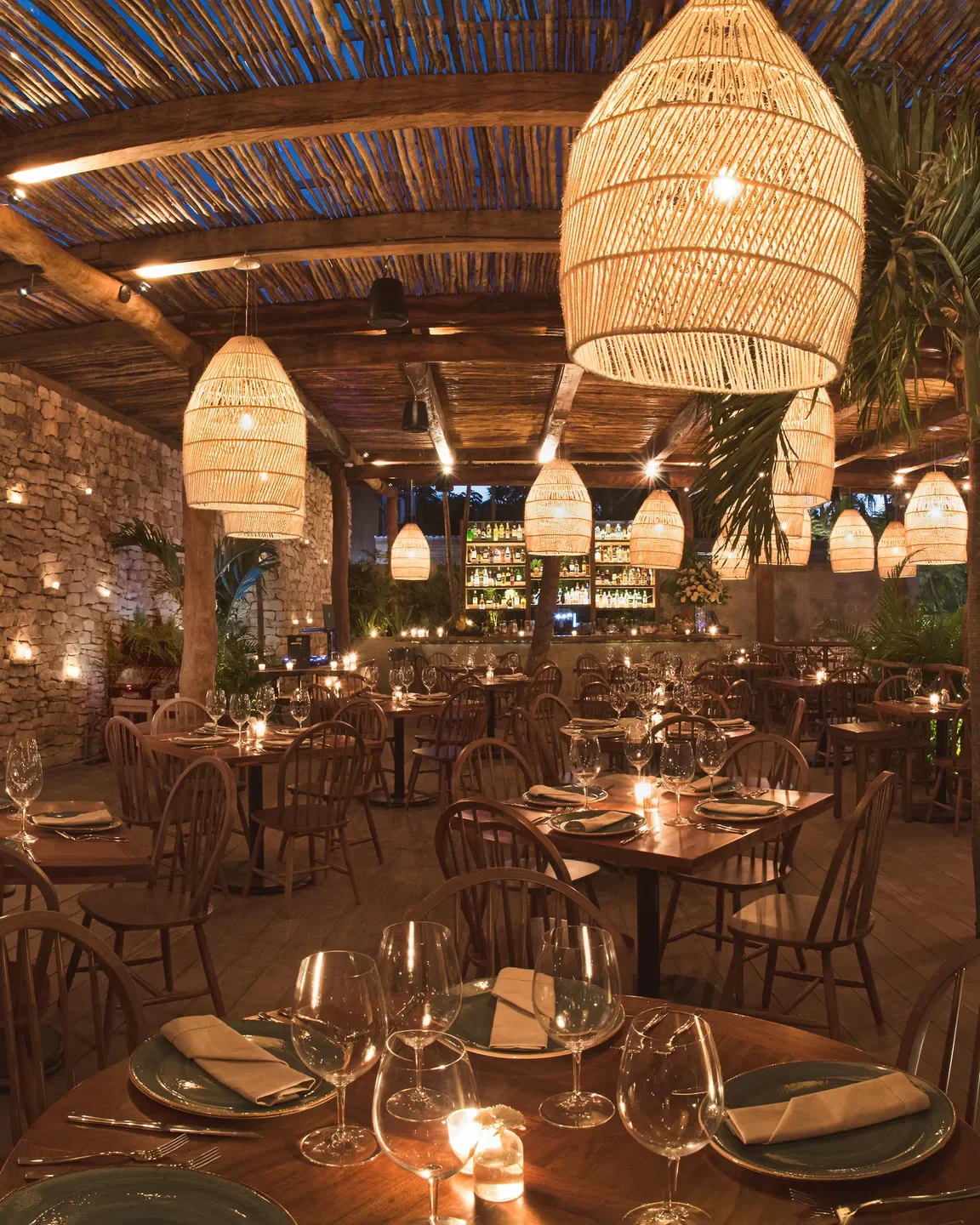 Cozy dining area at Rosa Negra in Tulum, featuring wicker lamps and candlelit tables.