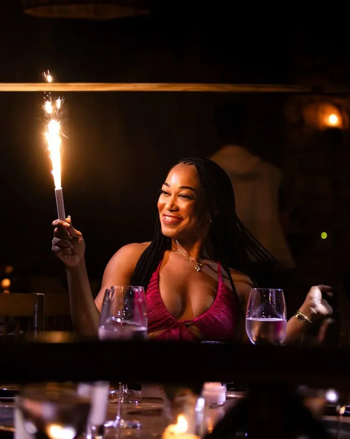 Woman celebrates at Rosa Negra Tulum, holding a sparkler at the nightclub.