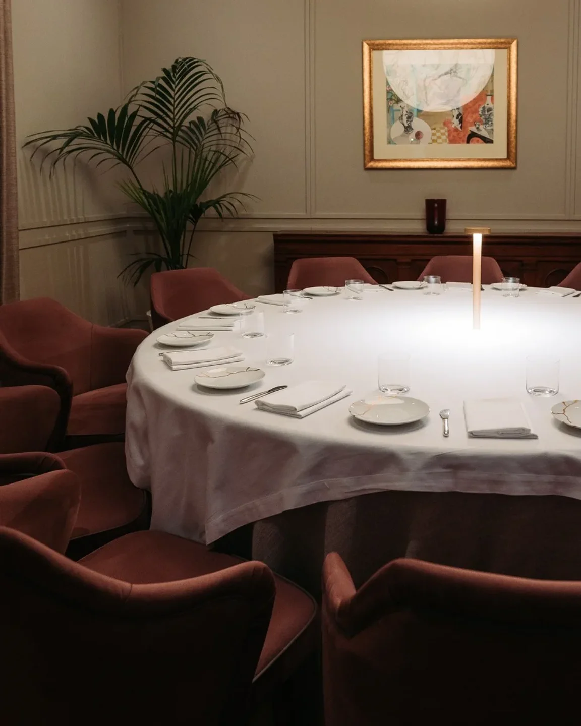 Rosami at The Villa Malta: elegant round dining table setting with plush chairs and art adornment.