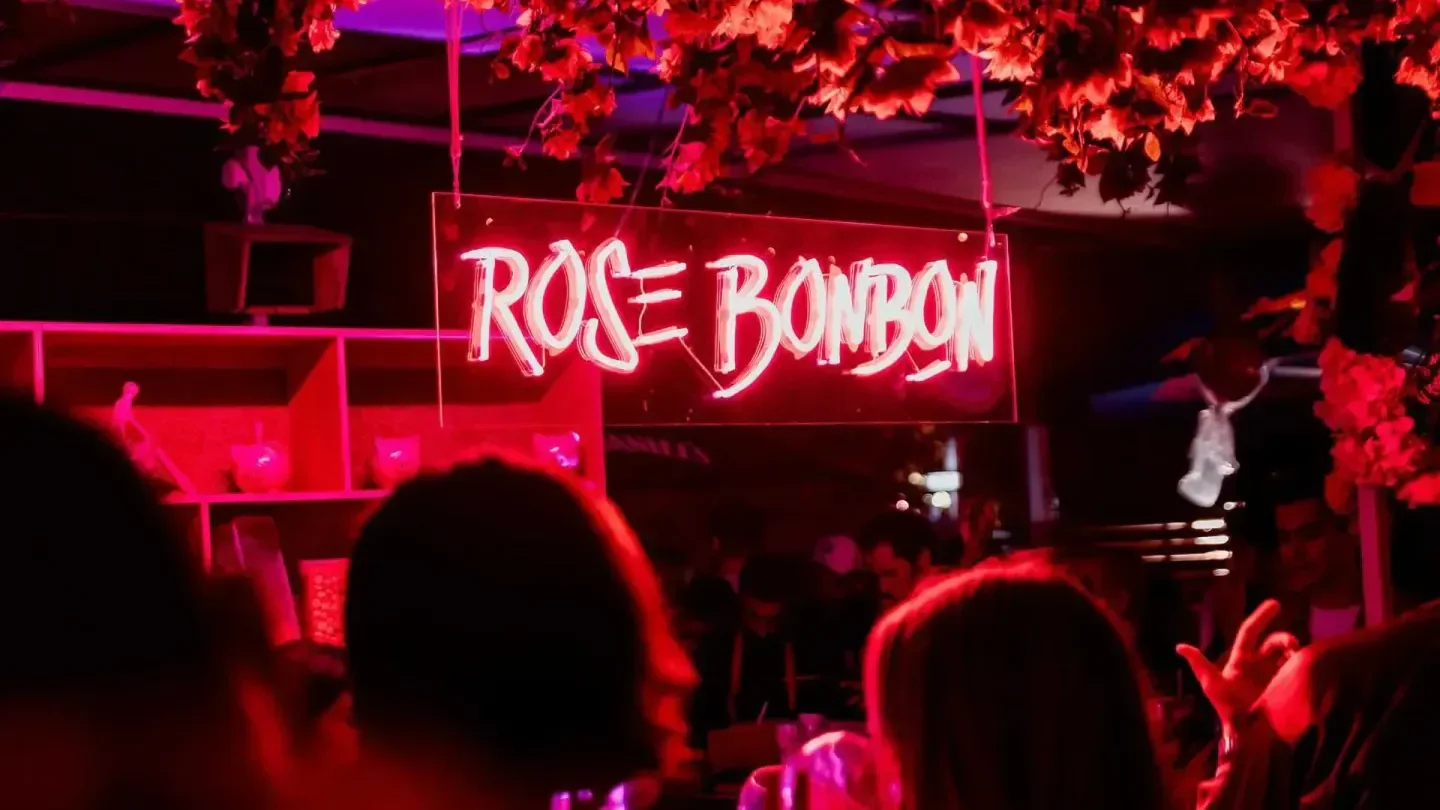 Neon sign at Rose Bonbon nightclub in Paris, glowing in a vibrant red hue.
