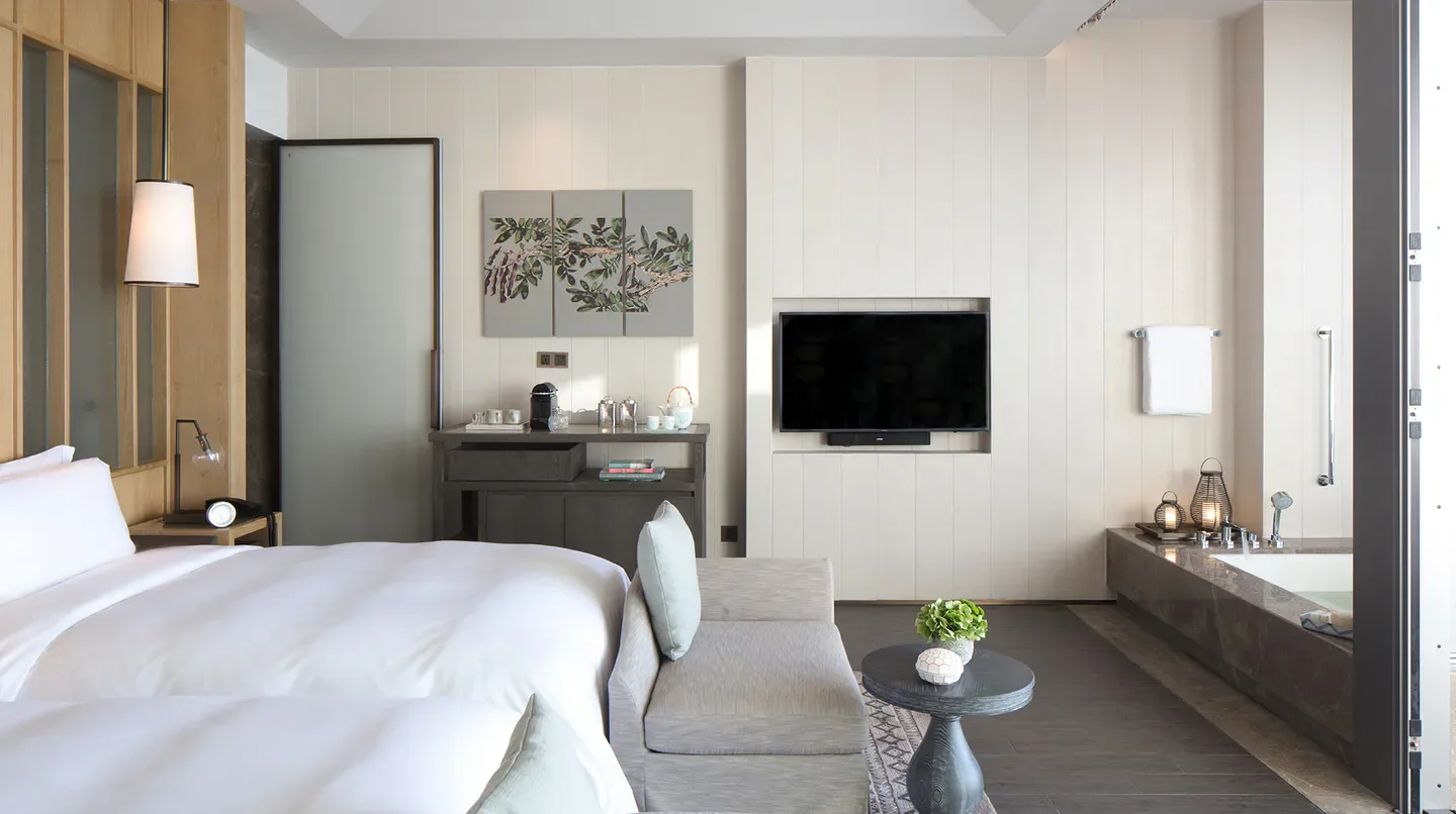Modern bedroom suite at Rosewood Sanya hotel in Sanya, China with bathtub view.