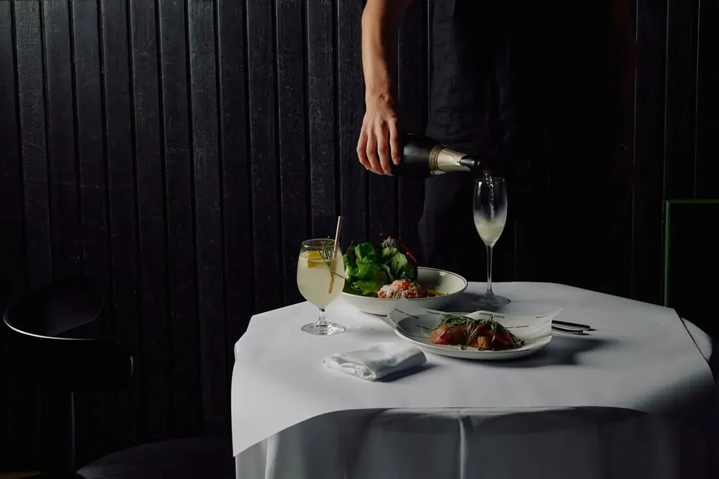 Champagne being poured at Saint George restaurant in Melbourne, with dishes on the table.