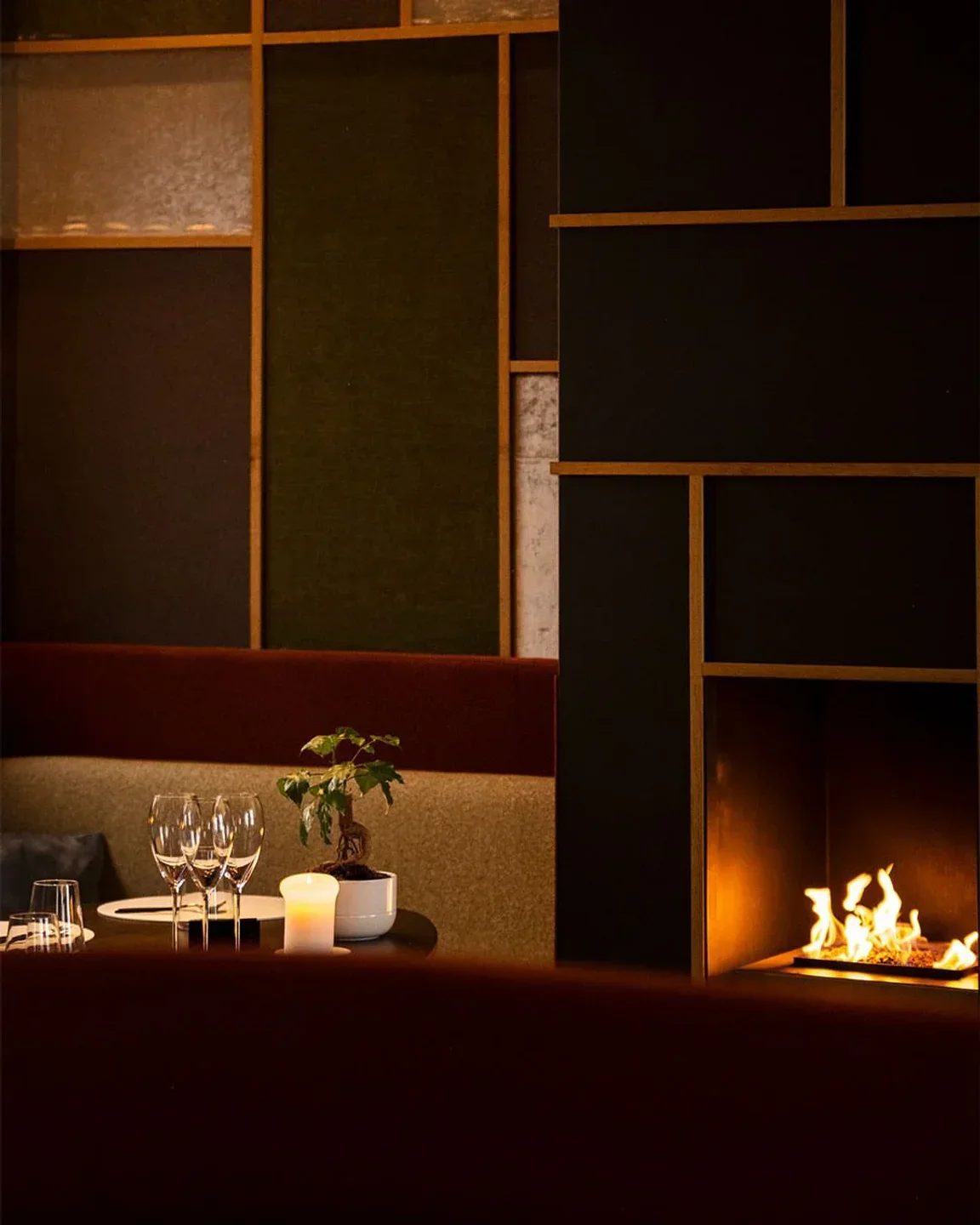 Cozy interior of Sans Cravate restaurant in Bruges, featuring fireplace and elegant table setting.