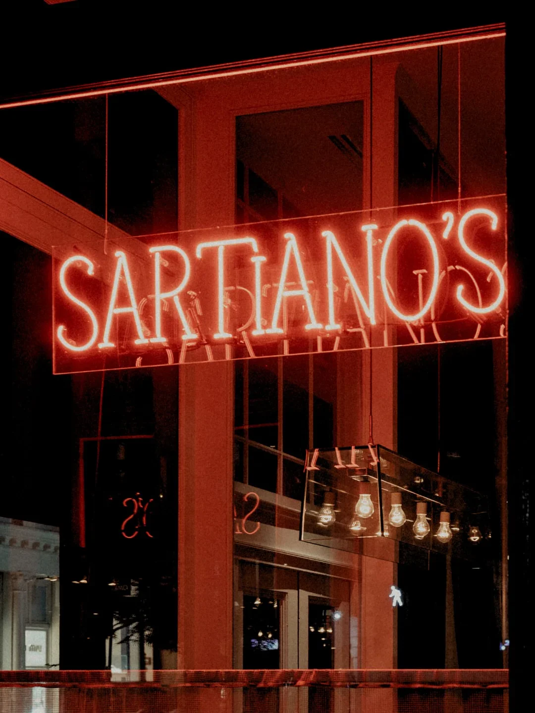 The glowing neon sign for Sartiano's restaurant in the city at night