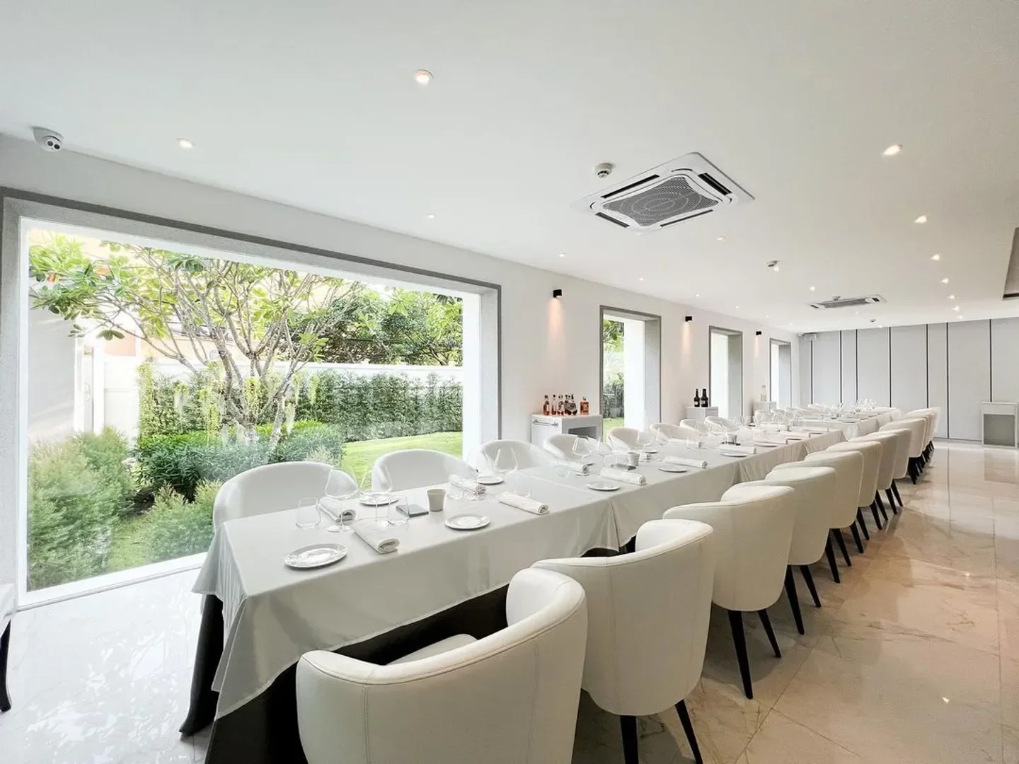 Elegant dining room at Savelberg Bangkok, featuring natural light and a garden view.