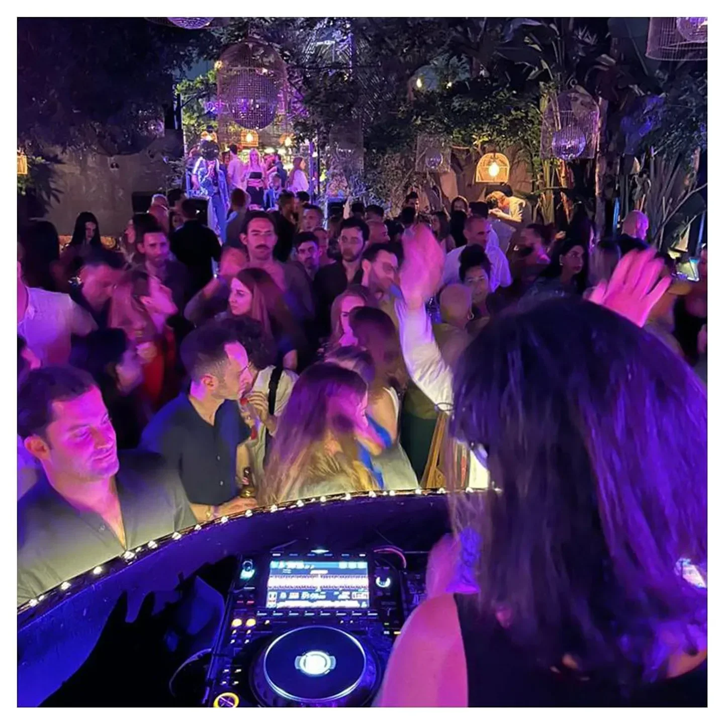 Nightclub scene at Secret Garden in Tel Aviv with DJ and dancing crowd.