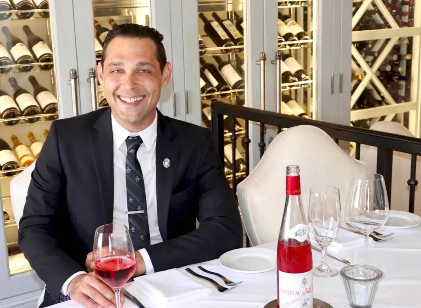 Smiling patron at Selanne Steak Tavern in Orange County enjoying a glass of wine.