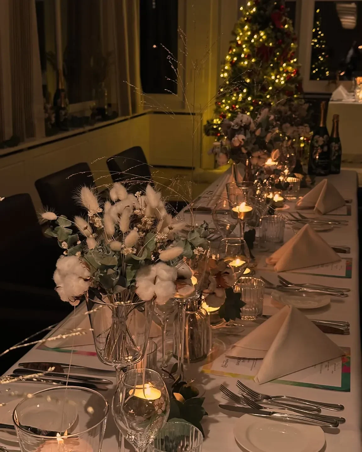 Cozy holiday table setting at Sens restaurant in Lucerne, featuring candles and floral arrangements.