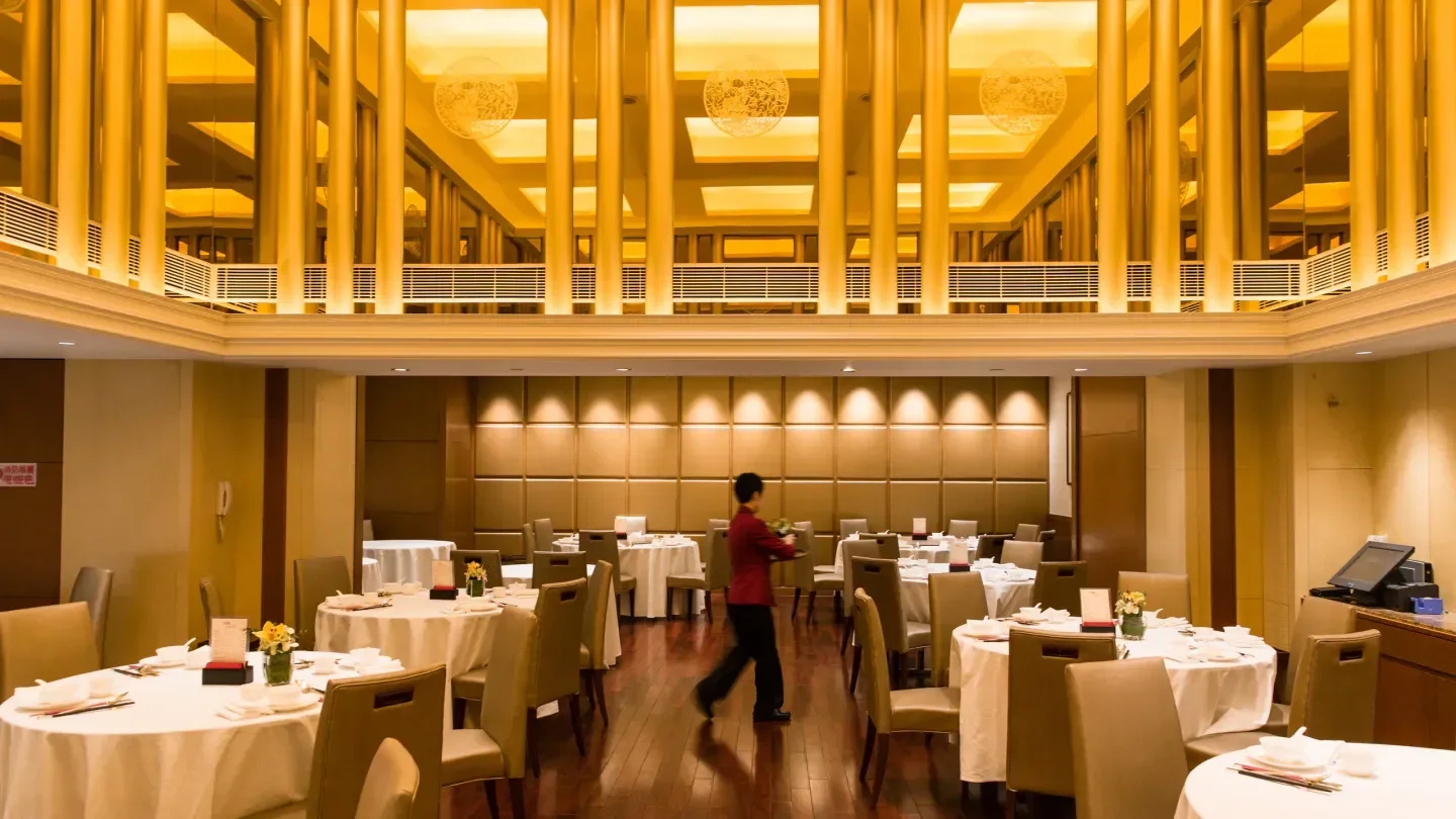 Elegant interior of Seventh Son (Wan Chai), Hong Kong restaurant with tables and staff.