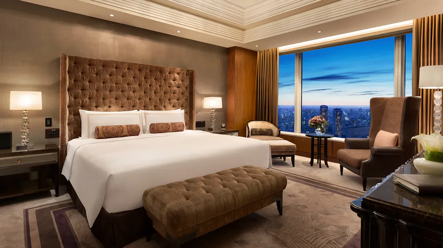 Luxury bedroom at Shangri-La Tokyo with stunning city views of Tokyo at twilight.