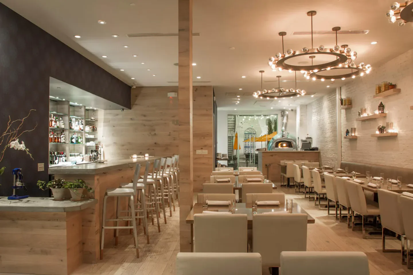 Interior of Shaya restaurant in New Orleans with bar, tables, and a pizza oven.