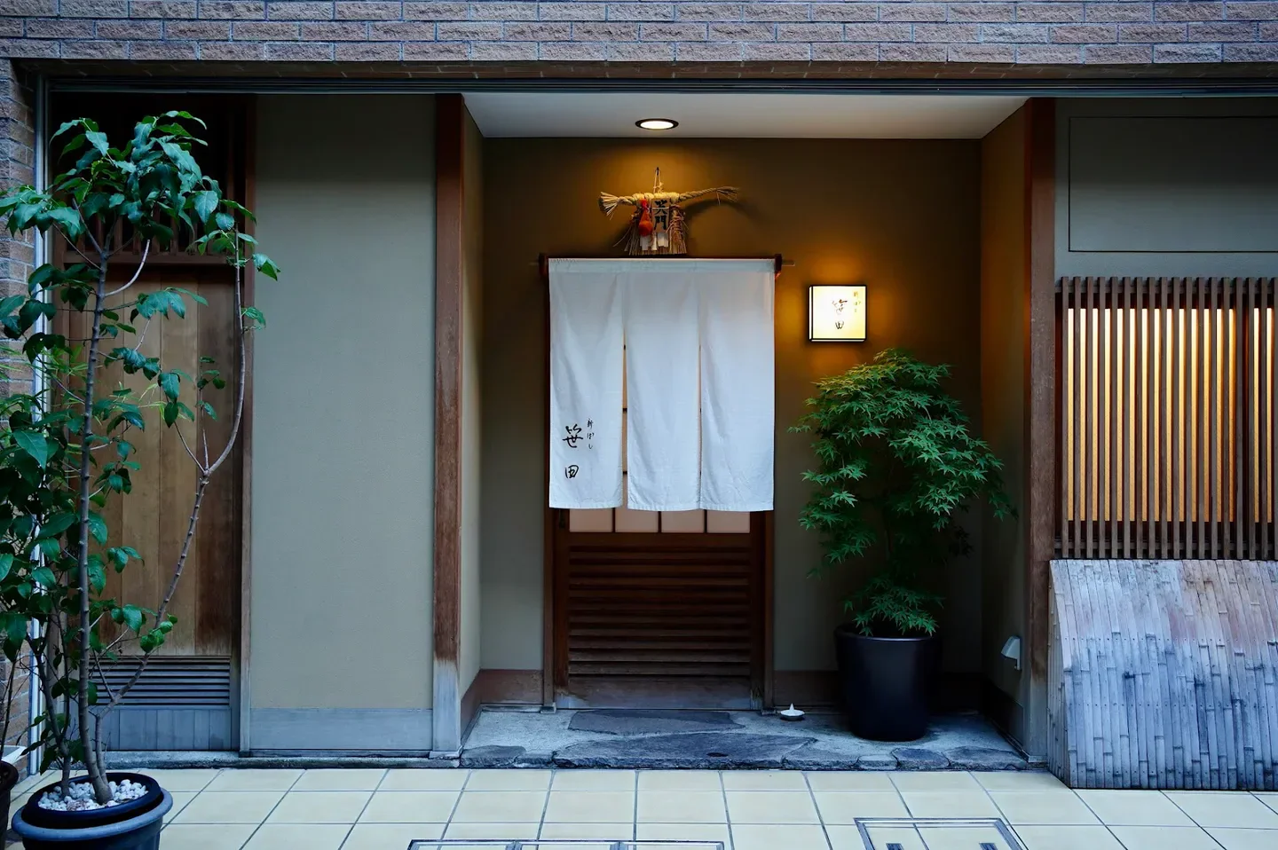 Entrance of Shimbashi Sasada restaurant in Tokyo, featuring traditional Japanese design and plants.