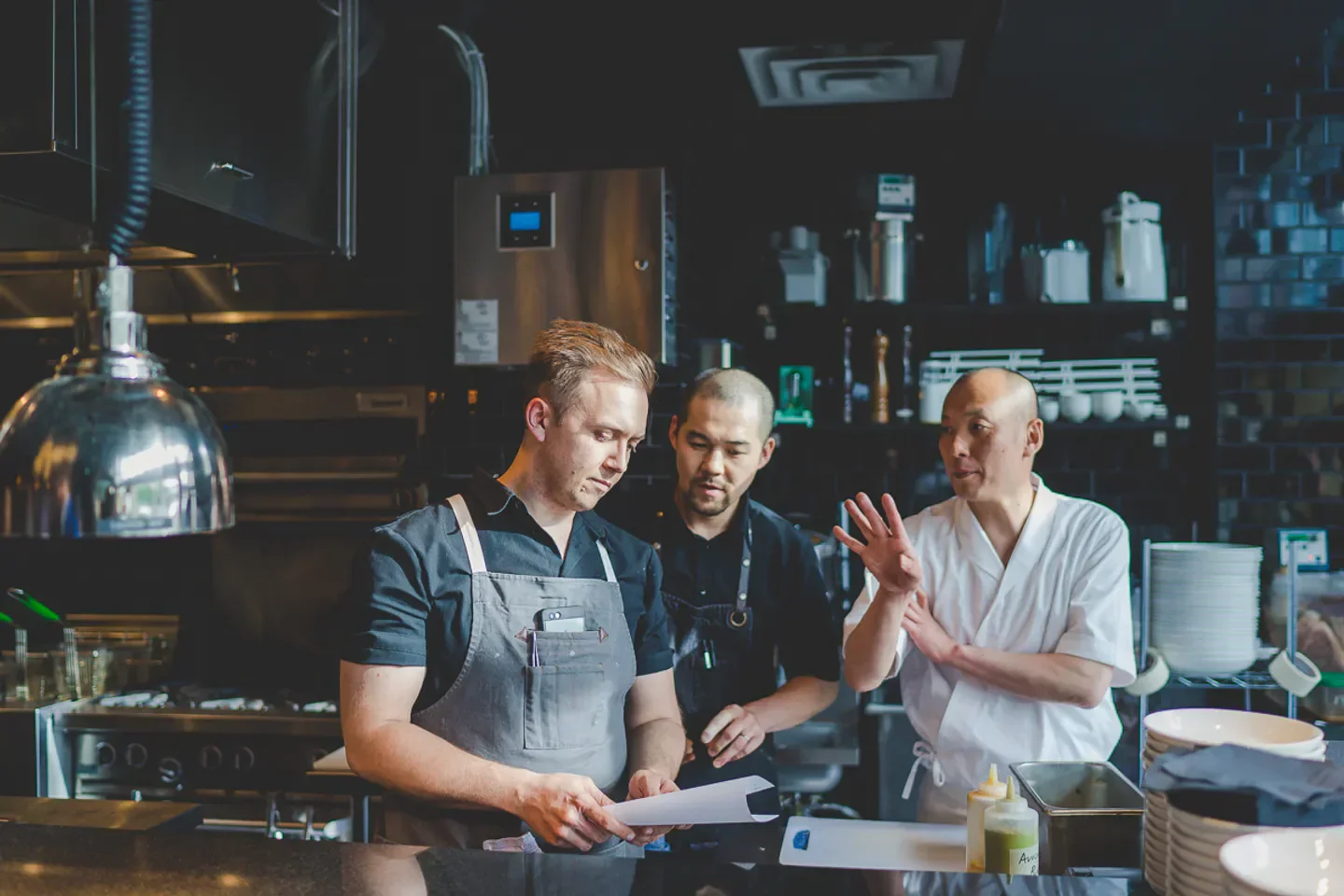 Chefs at Shokunin Calgary discussing menu in the restaurant kitchen, prepping for service.