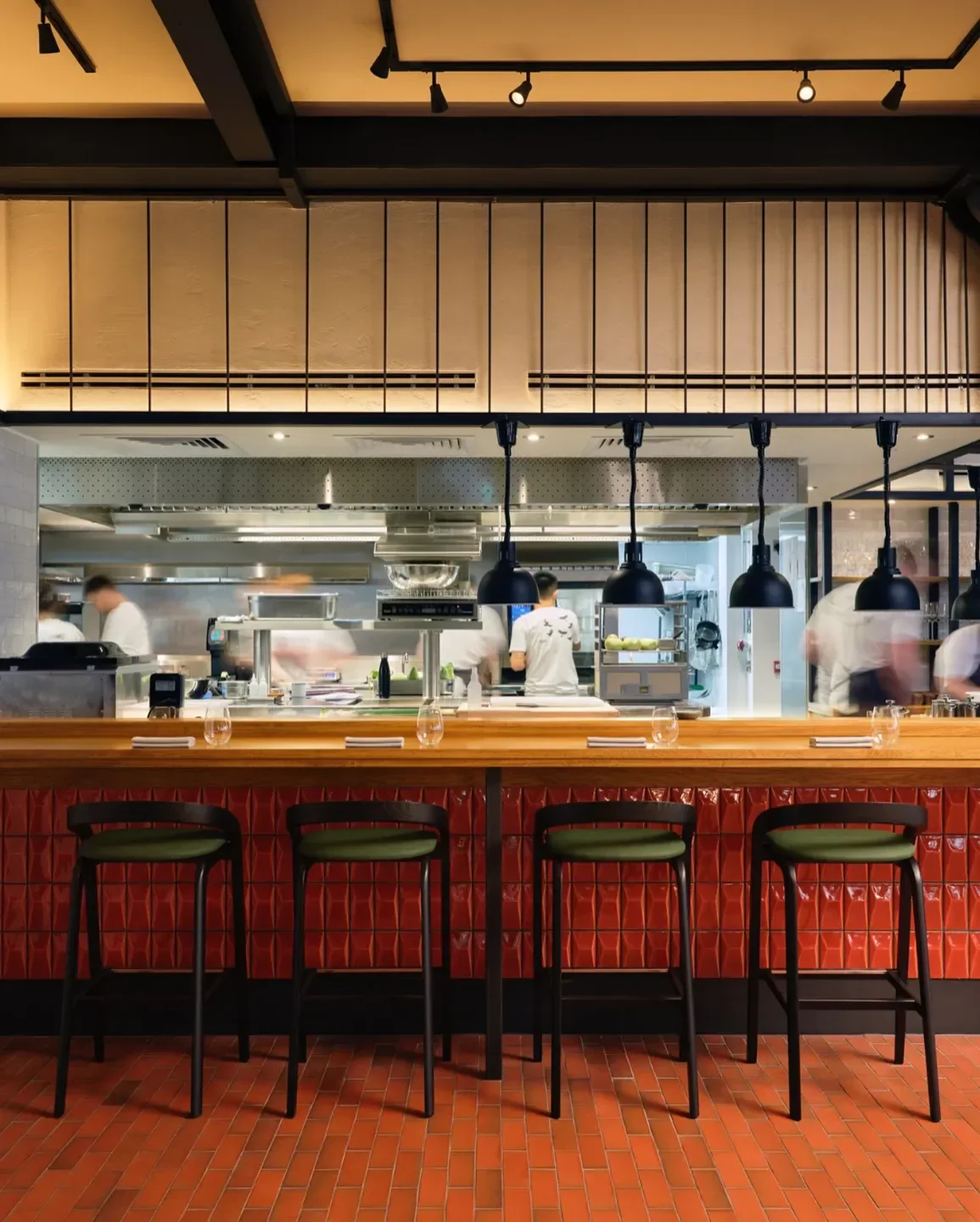 Interior view of SKOF restaurant in Manchester, featuring bar seating and kitchen activity.