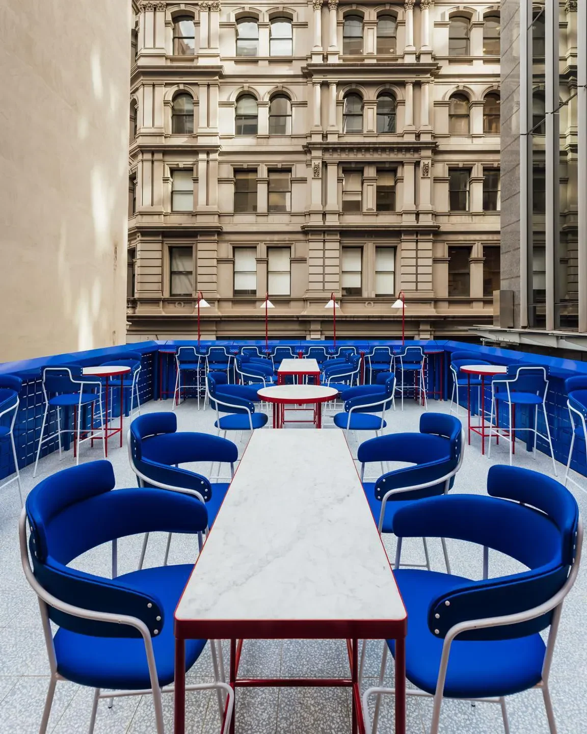 Stylish outdoor seating at Sojourn restaurant in Melbourne, with vibrant blue chairs and tables.