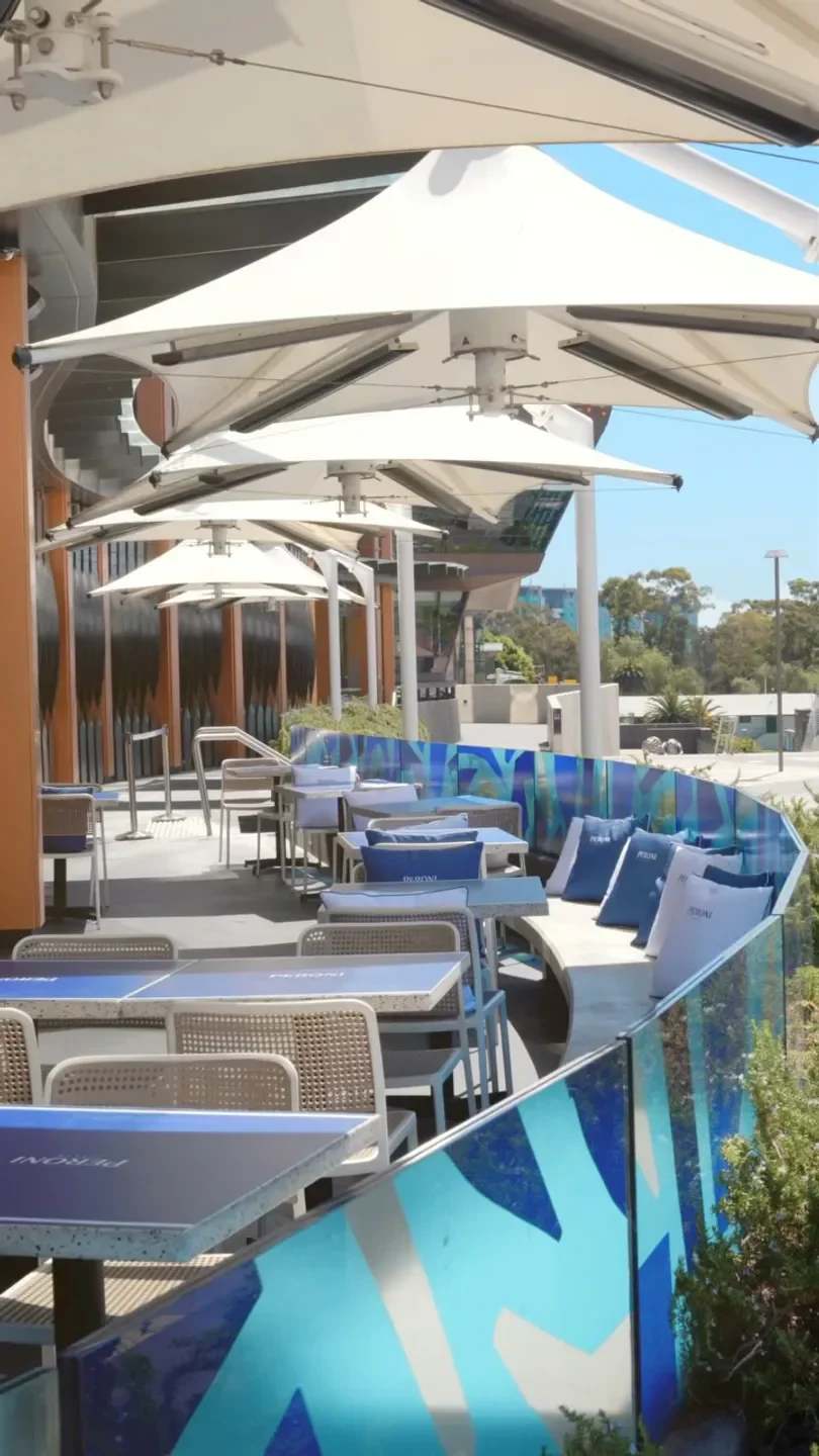 Outdoor seating at Sôl Rooftop restaurant in Adelaide, featuring shade sails and blue accents