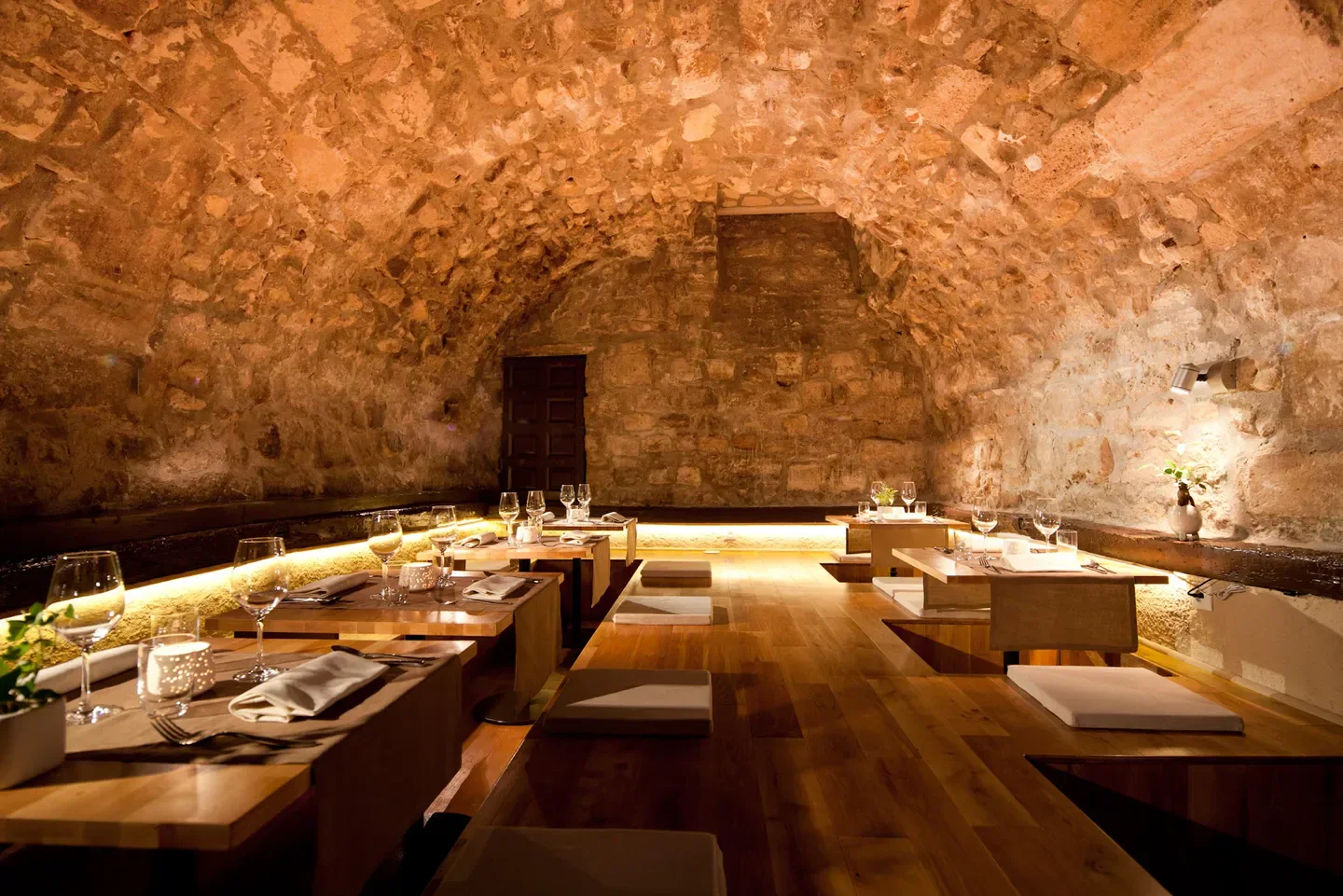 Cozy dining room at Sola restaurant in Paris, featuring stone walls and wooden tables.