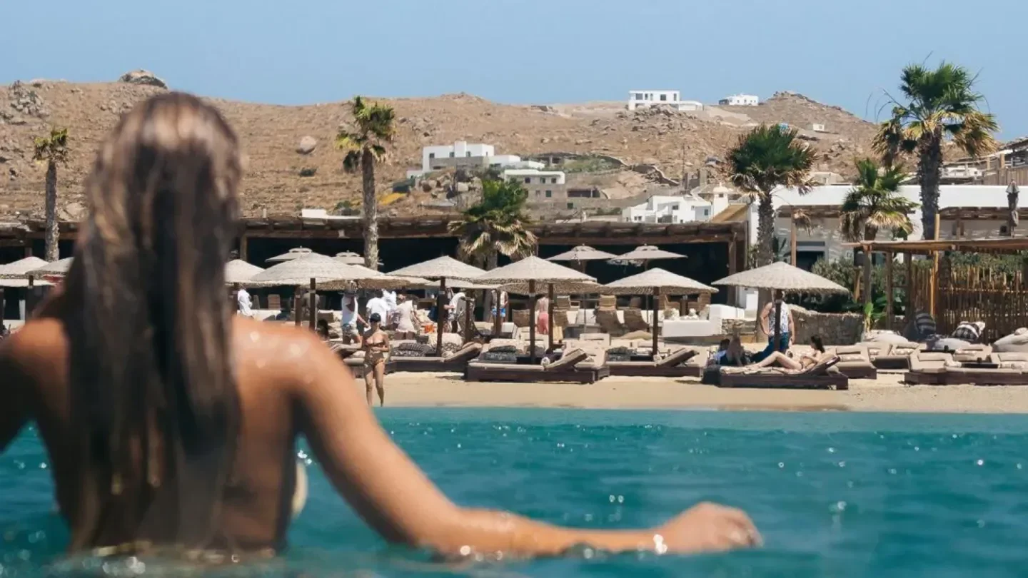 Beach scene at Solymar Mykonos with turquoise water and beach umbrellas.