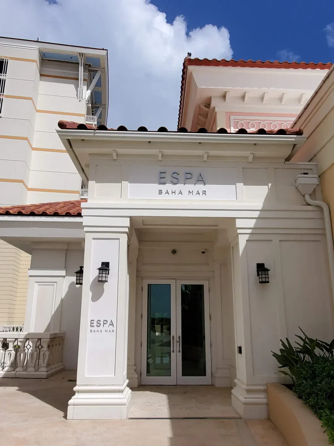 Entrance to Spa Botánico in The Bahamas with white columns and glass doors.
