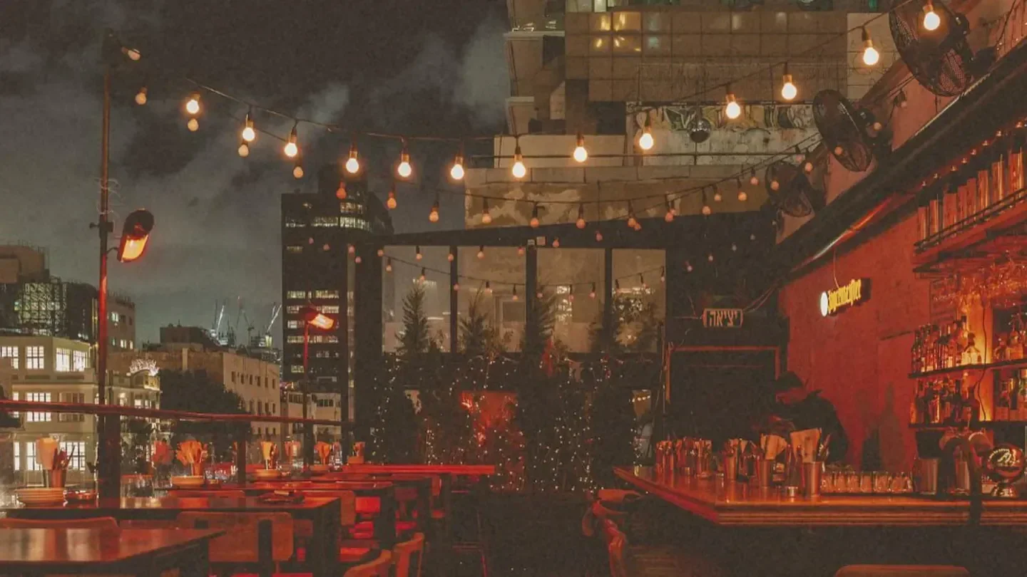 Rooftop bar at Speakeasy Tel Aviv at night, with fairy lights and city views