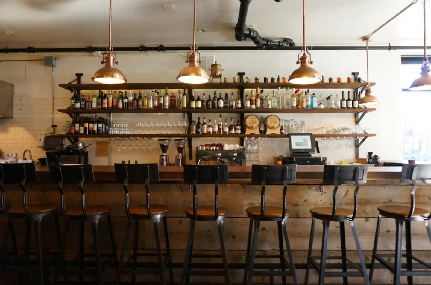 Interior view of the bar at Spuntino in Denver, featuring bottles and bar stools.