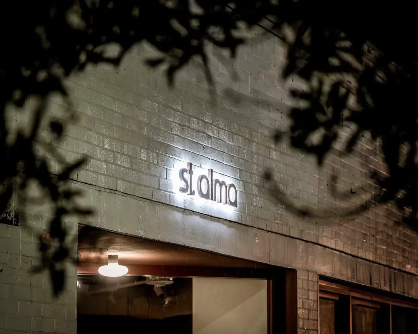 St. Alma restaurant in Sydney illuminated at night, showcasing the venue's entrance.