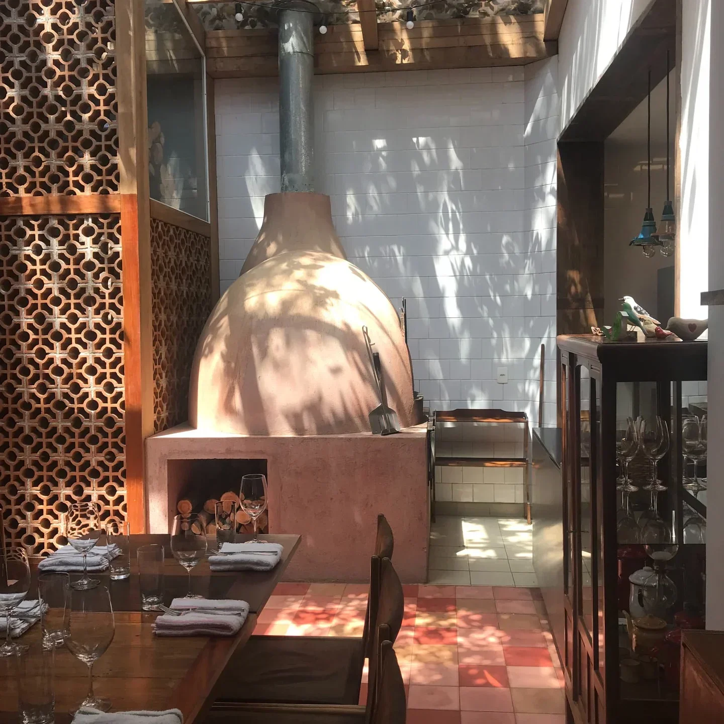 Interior of Sud, o pássaro verde Café in Rio de Janeiro, with a rustic oven and dining tables.