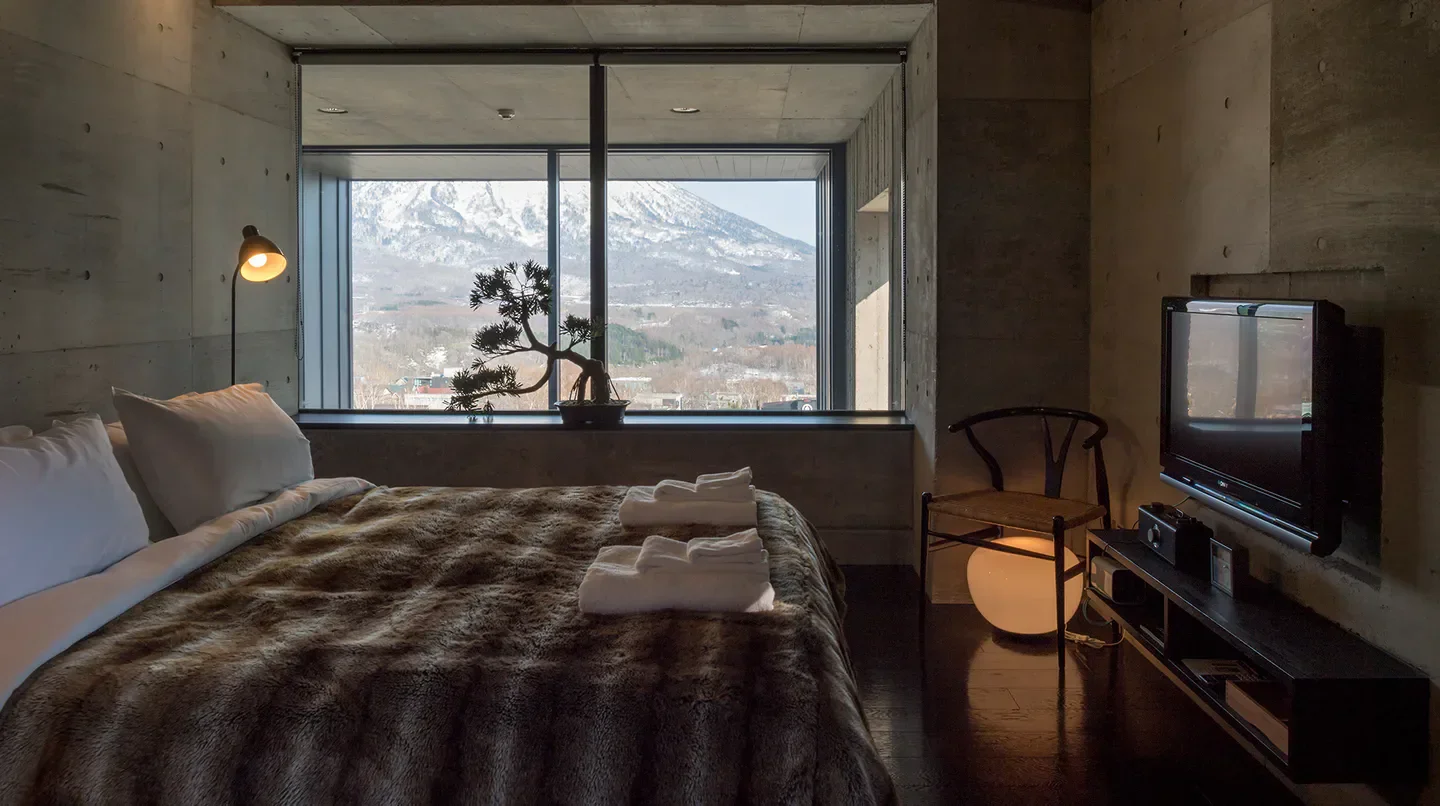 Cozy bedroom at Suiboku Hirafu hotel in Hokkaido, featuring mountain views and modern design.